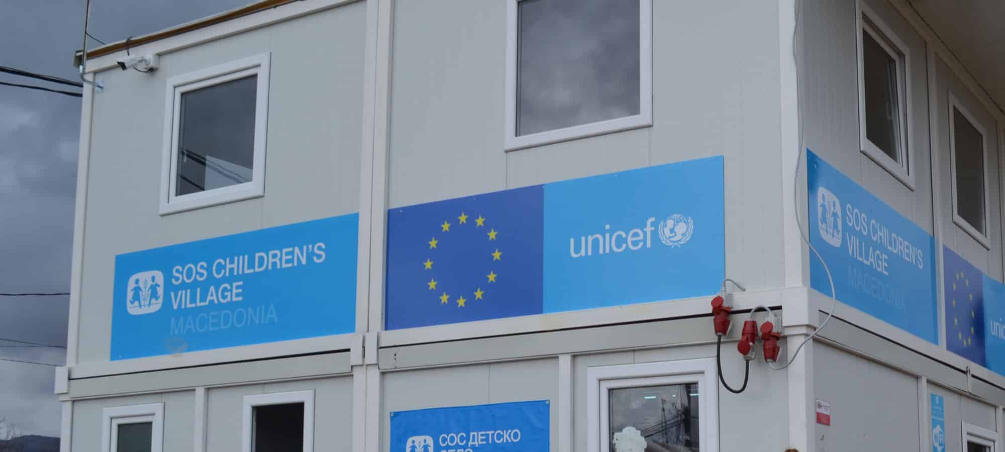Et toetasjes hus bygget opp av containere med SOS-barnebyers og Unicefs logo. Trygge soner for lek er en del av SOS-barnebyers nødhjelpsarbeid. Foto: Katerina Ilievska