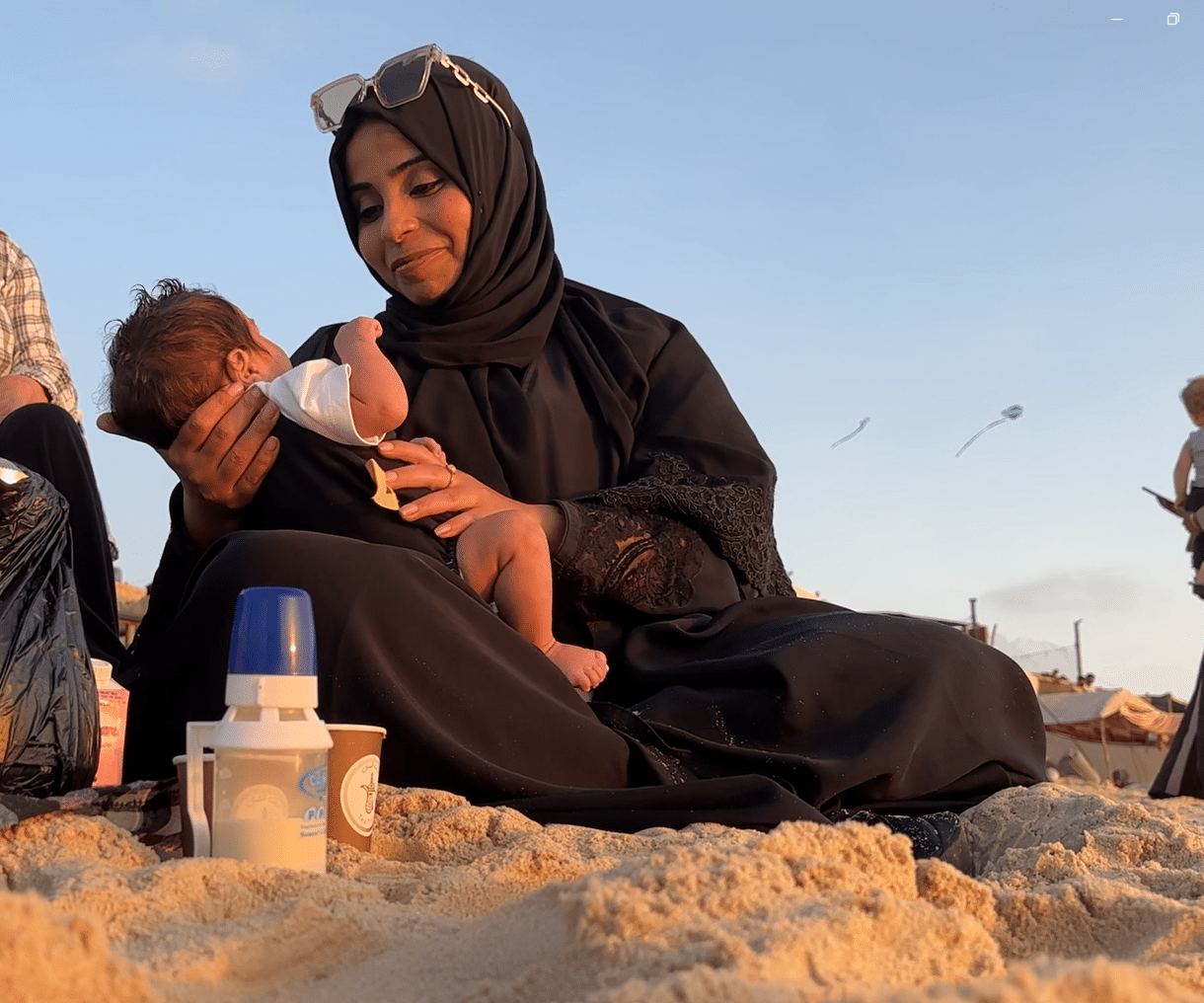 En kvinnelig SOS-arbeider i Gaza holder lille Karam, en fire måneder gammel baby, i armene og smiler ned mot ham. Foto Lama Qattush
