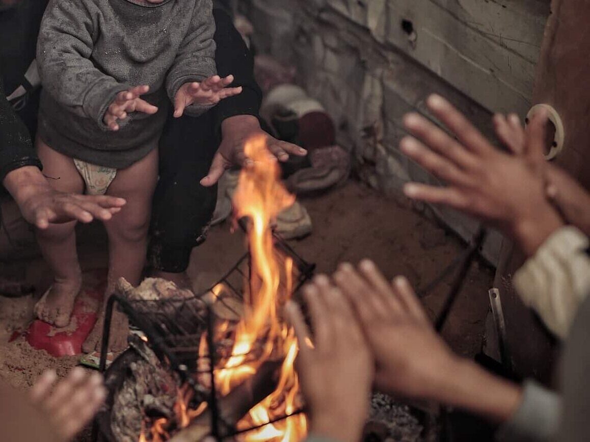Barn varmer seg rundt et bål i Gaza. Fotograf: Hosny Salah. Bli SOS-fadder